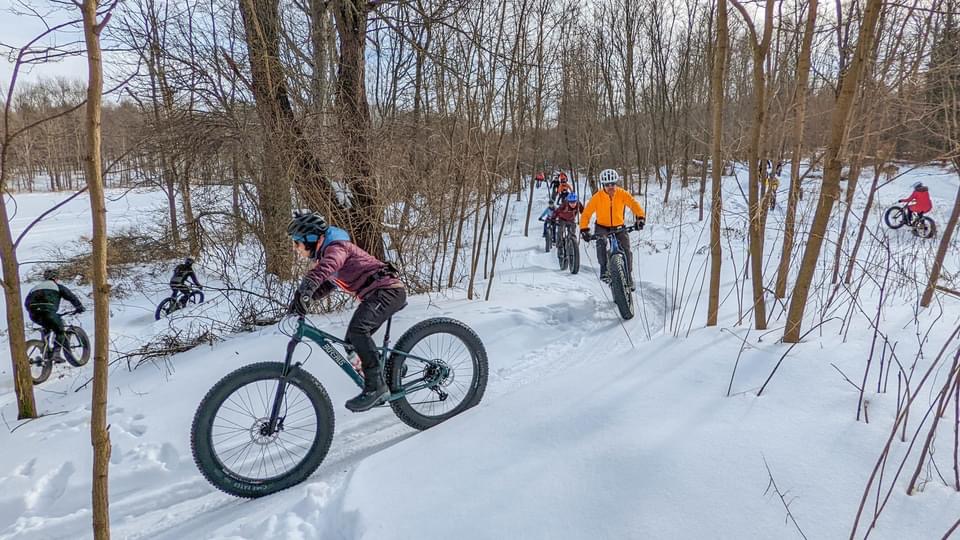 Group of people mountain biking in the snow.